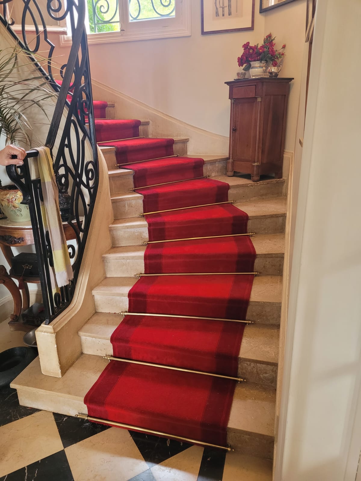 Escalier en marbre habillé d'un tapis rouge avec tringles laiton, baie lumineuse